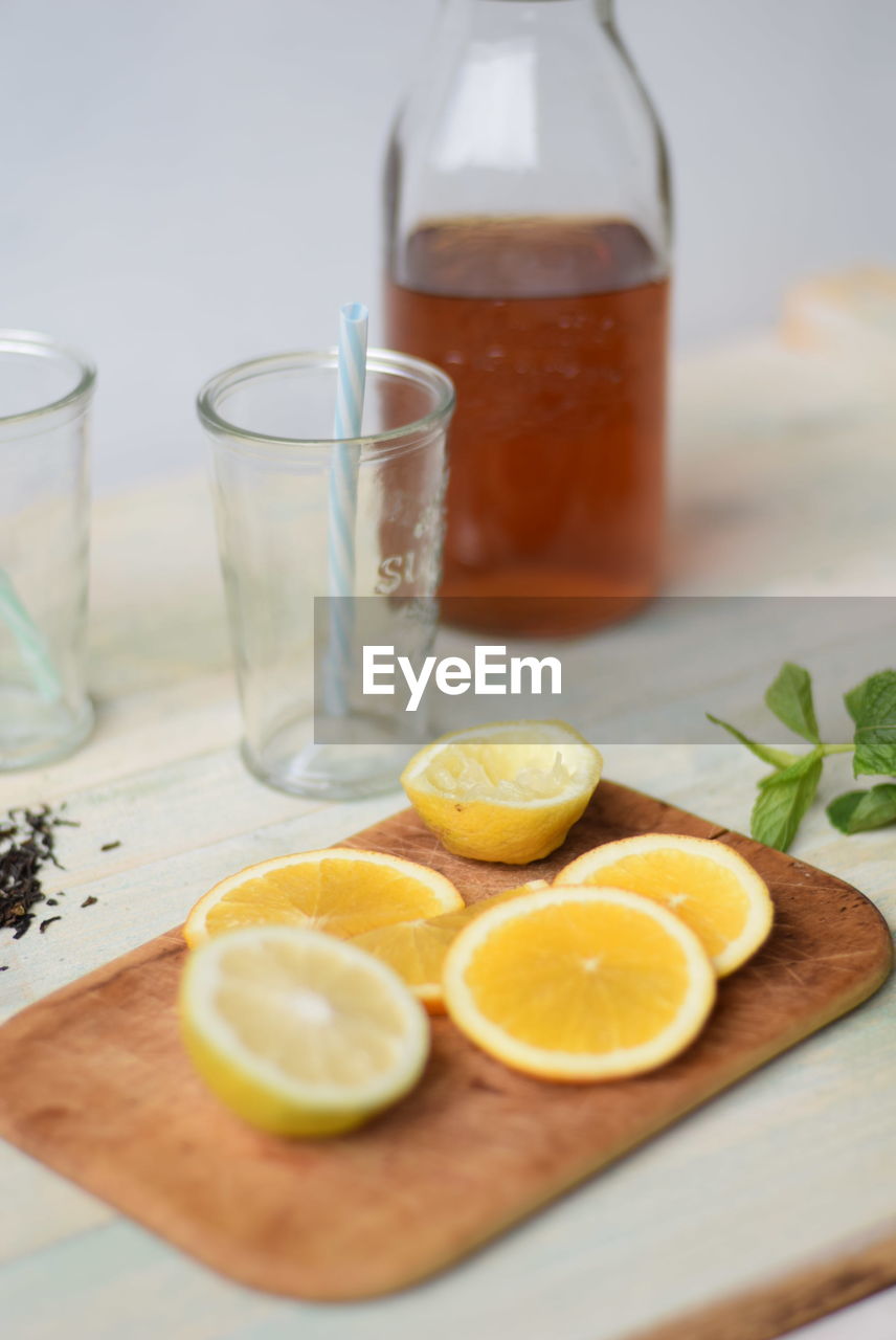 Slice lemons on wooden board by drinking glass with straws and jar of honey