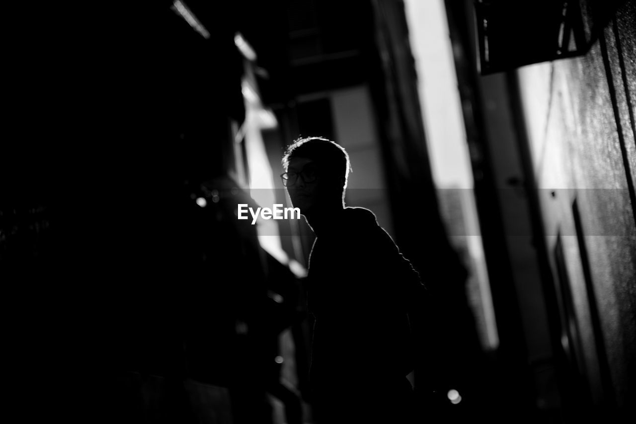 Silhouette man standing at alley during night