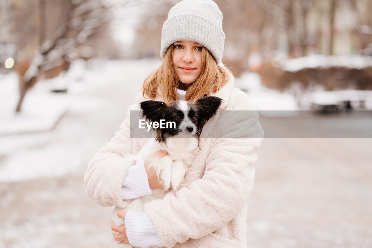 Portrait of girl holding dog while standing outdoors