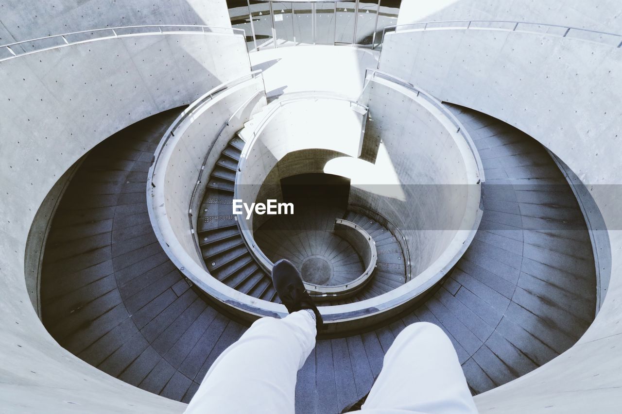 Low section of man against spiral staircase