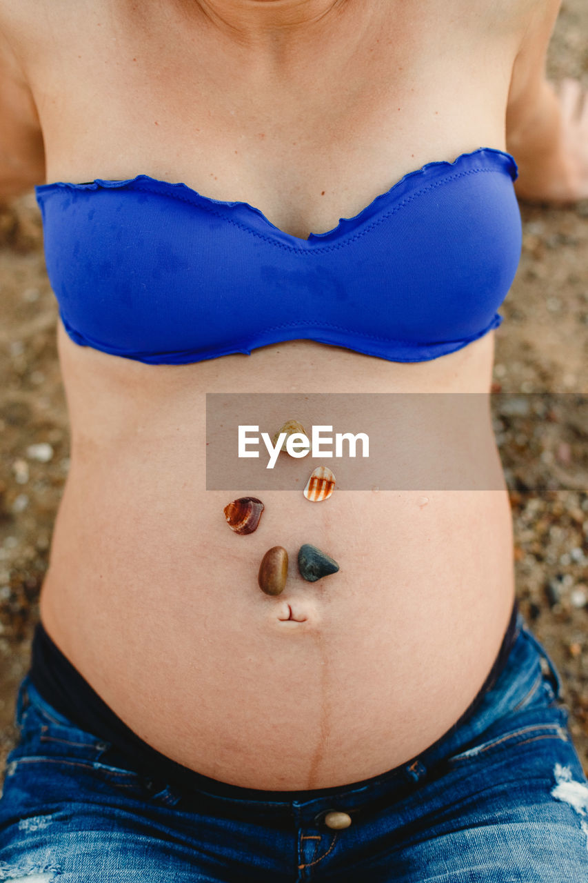 Midsection of pregnant woman with shells on stomach
