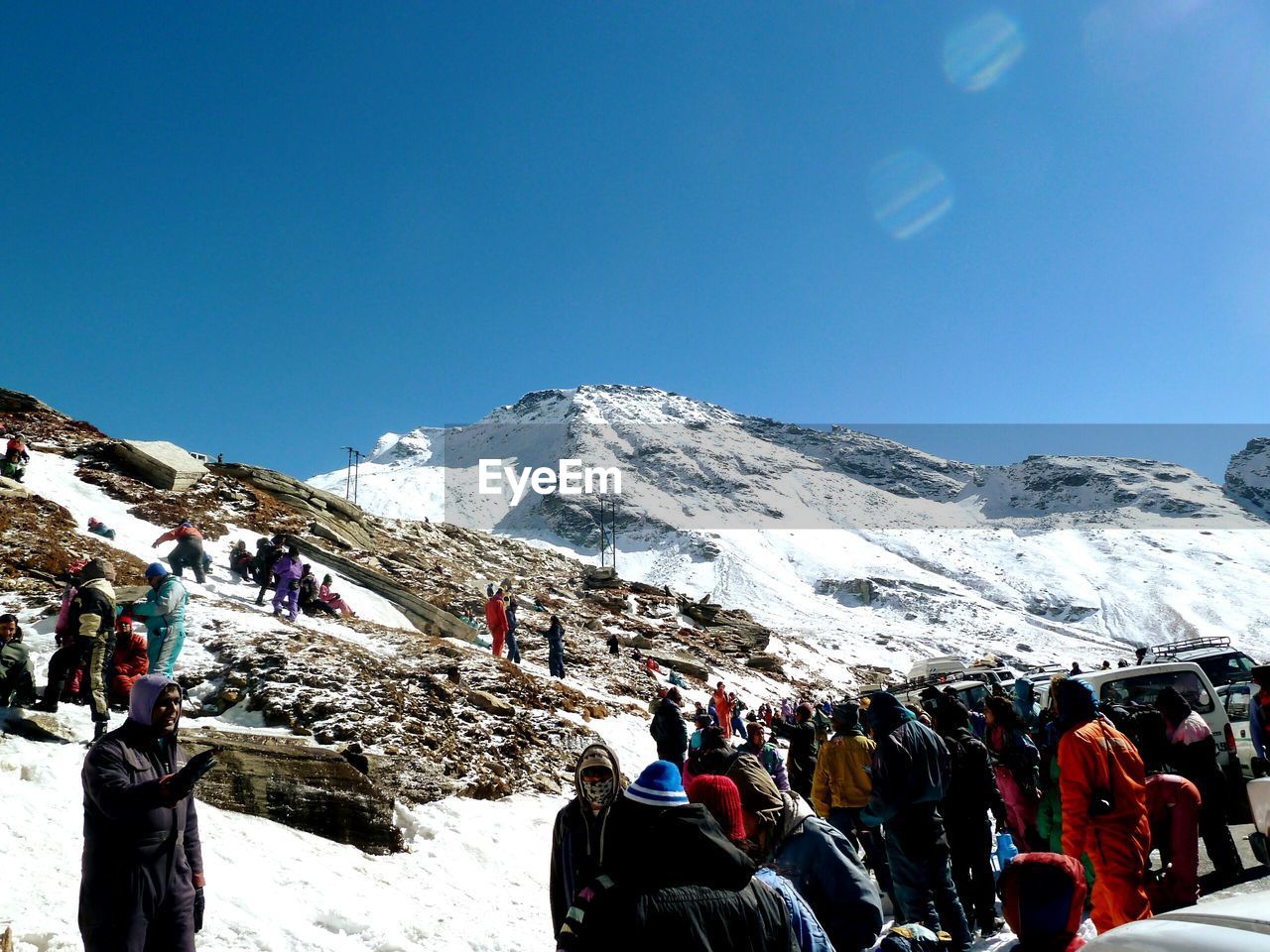 People on snowcapped mountains against clear blue sky