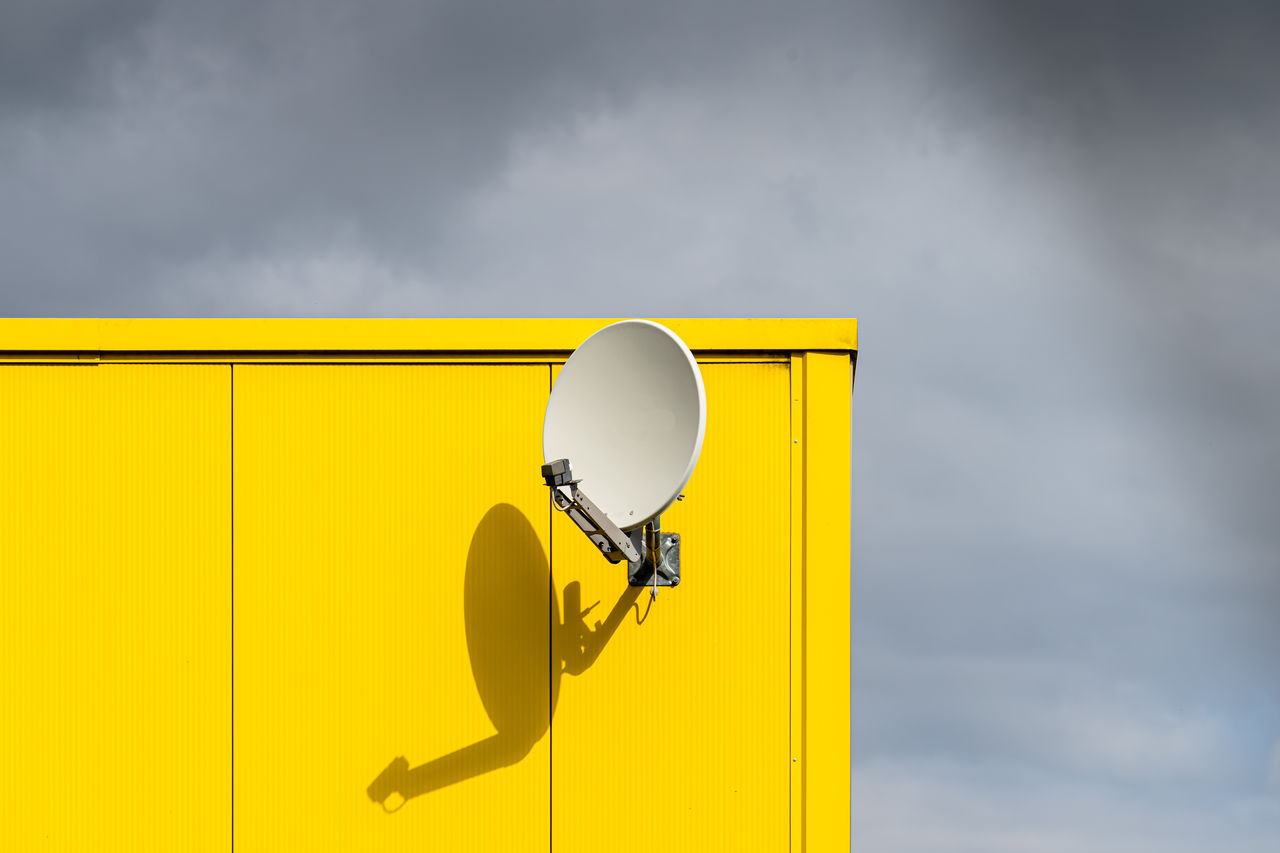 Satellite dish against yellow wall