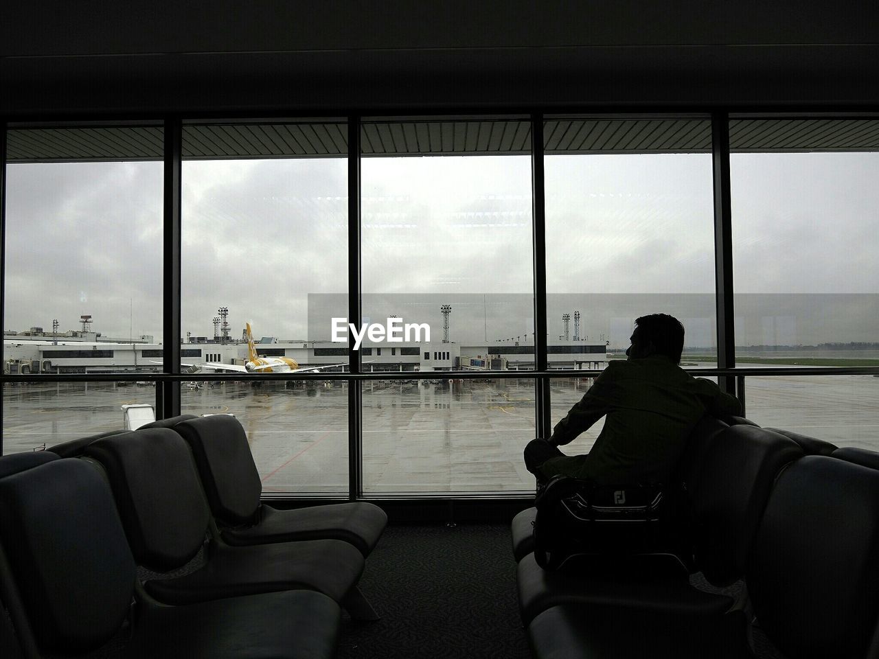Silhouette man sitting on seat at airport terminal
