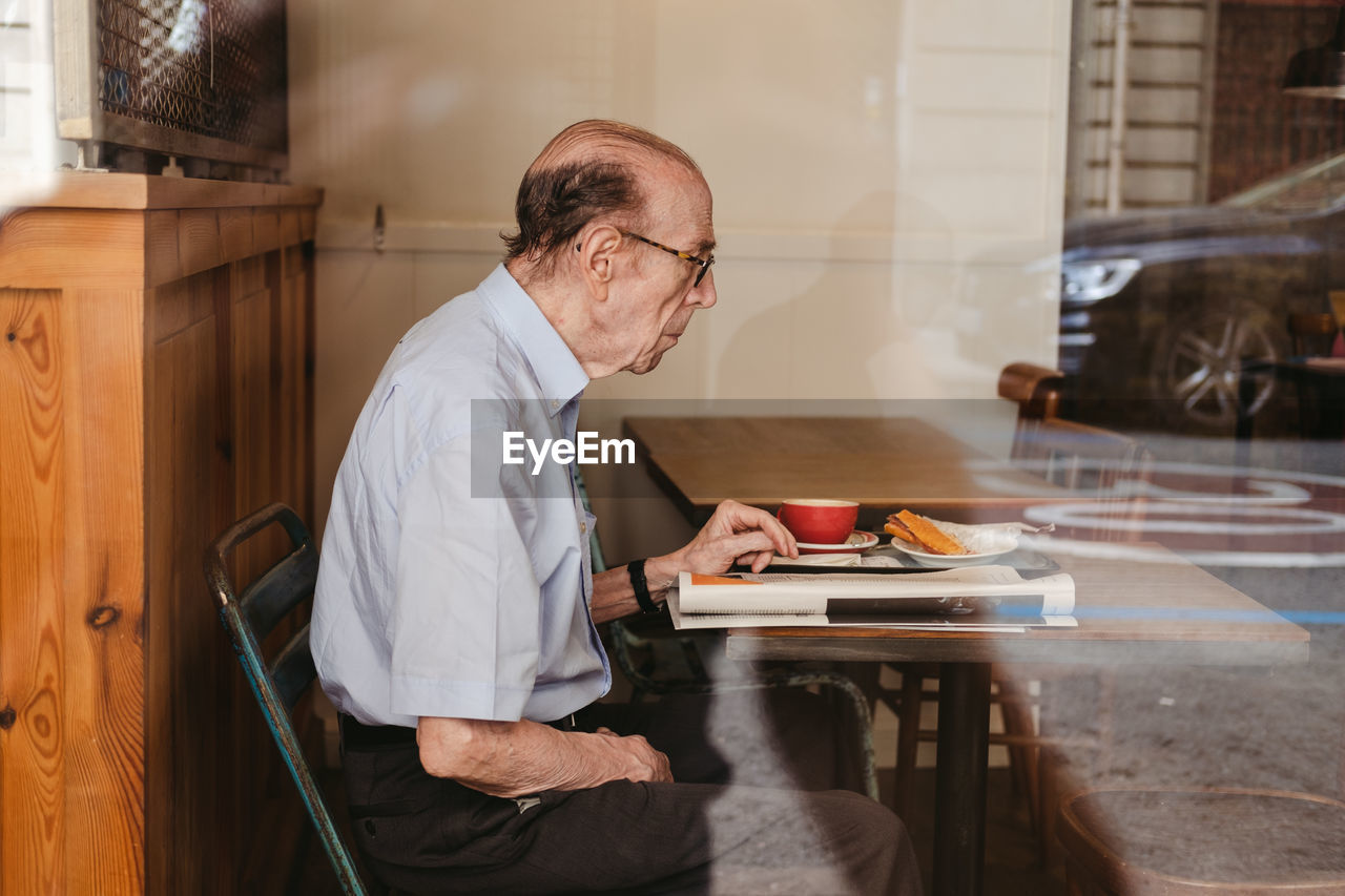 MAN SITTING ON TABLE AT CAFE