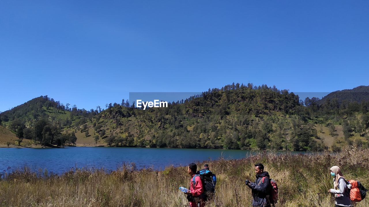 PANORAMIC VIEW OF PEOPLE ON LAKE AGAINST CLEAR BLUE SKY