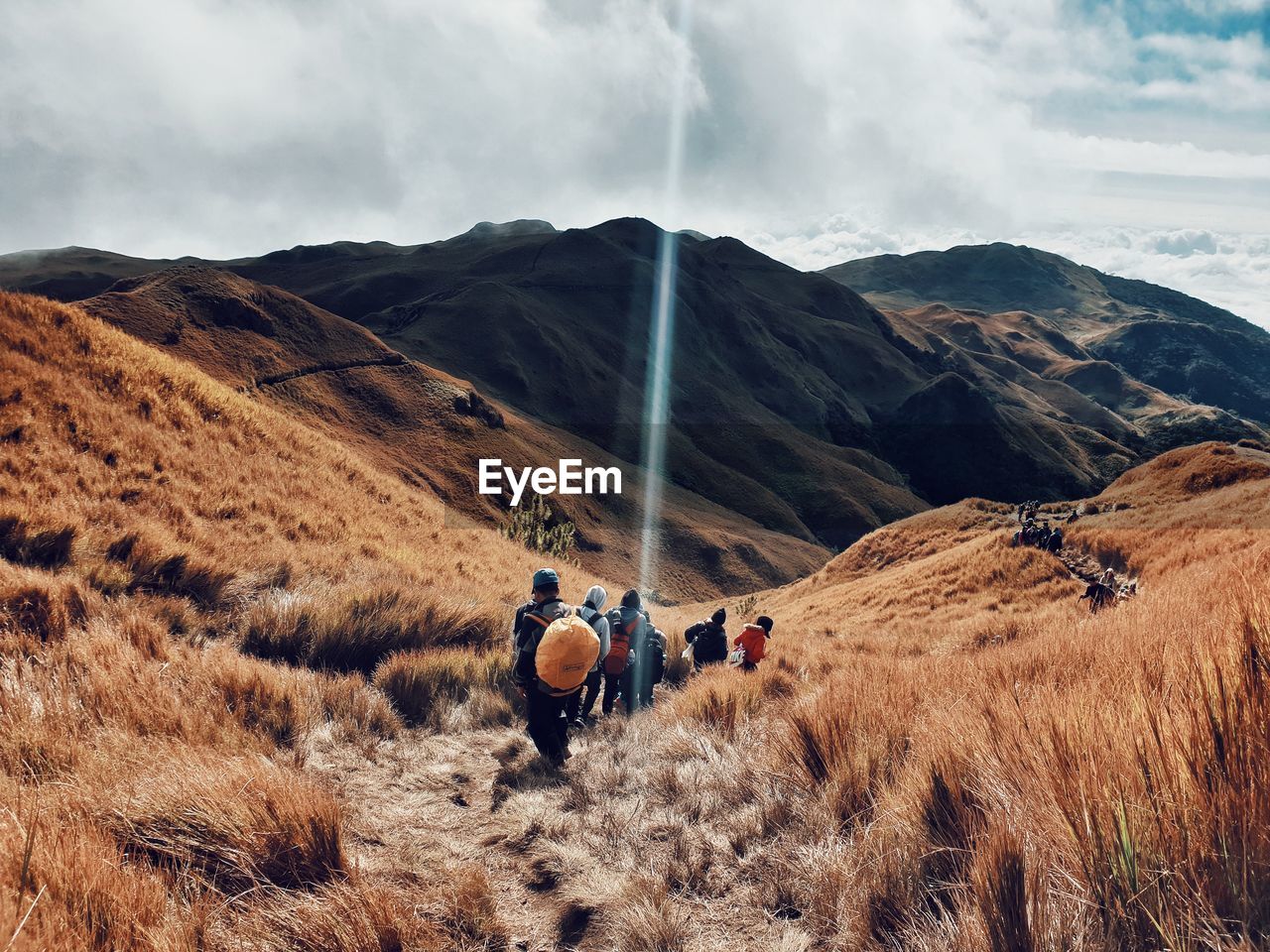 Rear view of people walking on mountain against sky