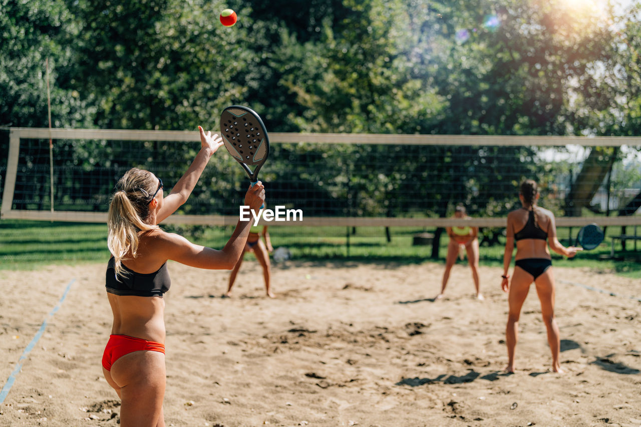 Female friends playing beach tennis