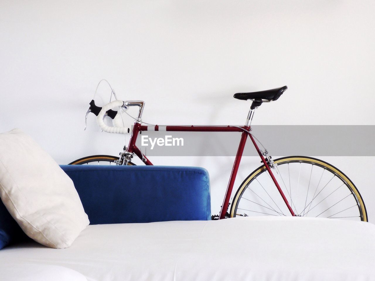 transportation, bicycle, indoors, no people, land vehicle, mode of transportation, stationary, white color, copy space, wall - building feature, absence, still life, studio shot, pillow, travel, wheel, furniture, home interior, day