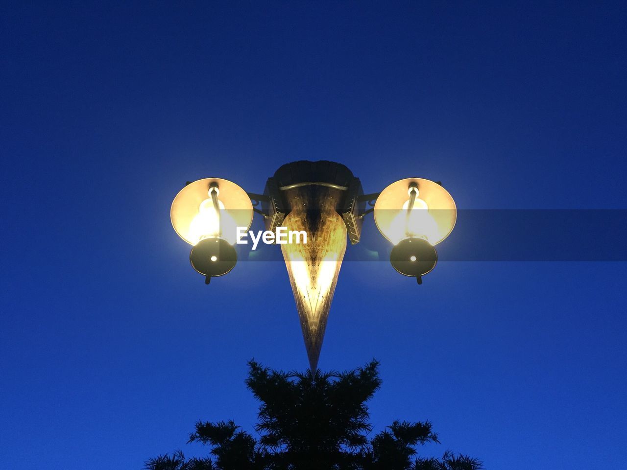 LOW ANGLE VIEW OF ILLUMINATED LAMP AGAINST BLUE SKY