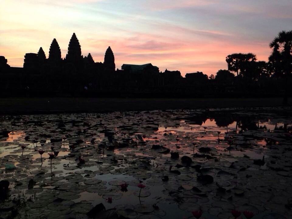 River by silhouette angkor wat against sky at sunset