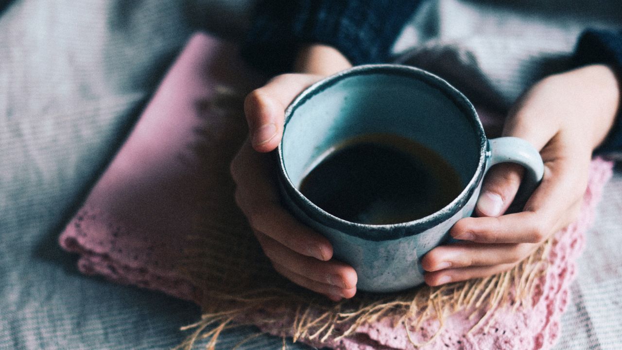 Cropped hands holding tea cup on table