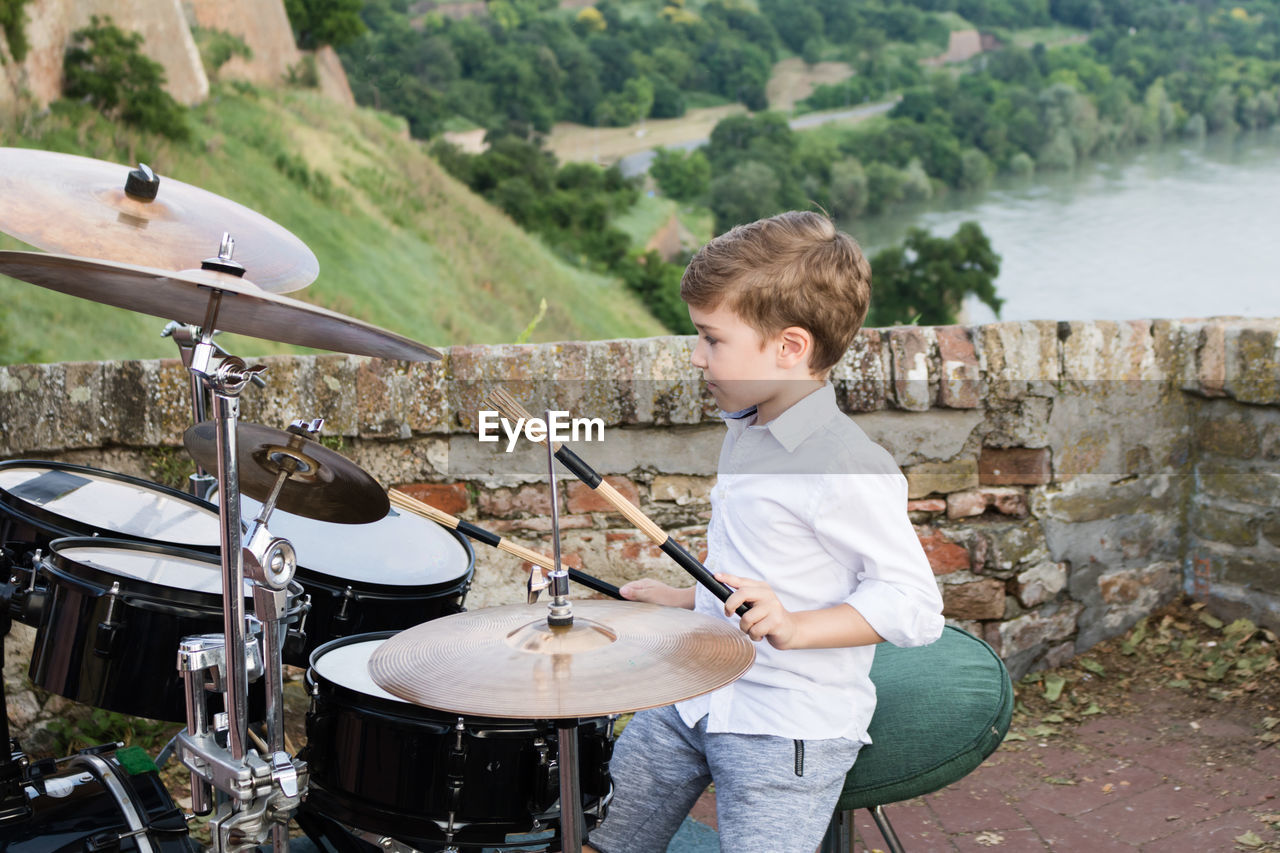 Boy playing drum kit outdoors