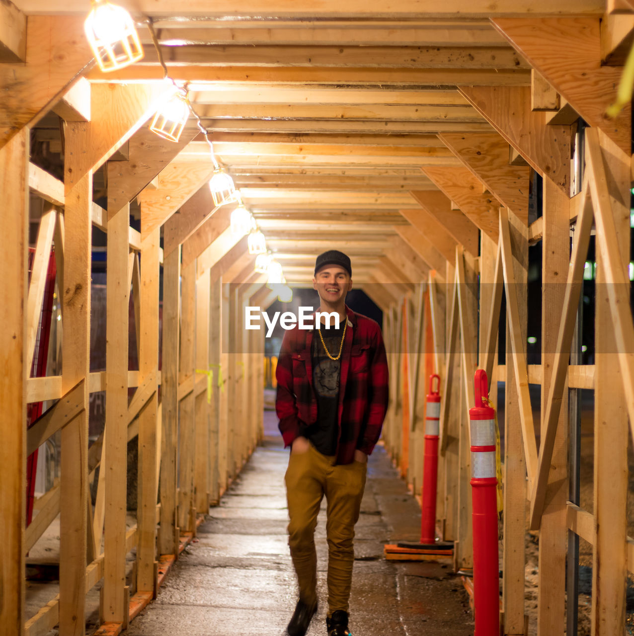 Portrait of teenager boy walking in illuminated wooden covered walkway
