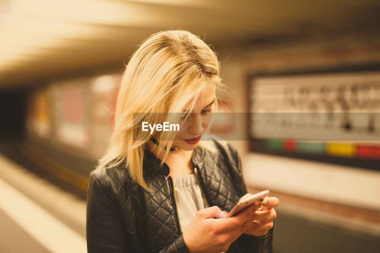 Young woman using phone at subway station