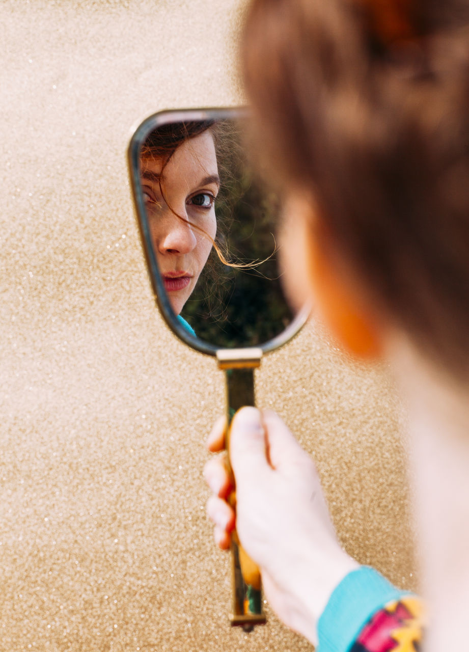 Cropped image of young woman holding mirror with reflection