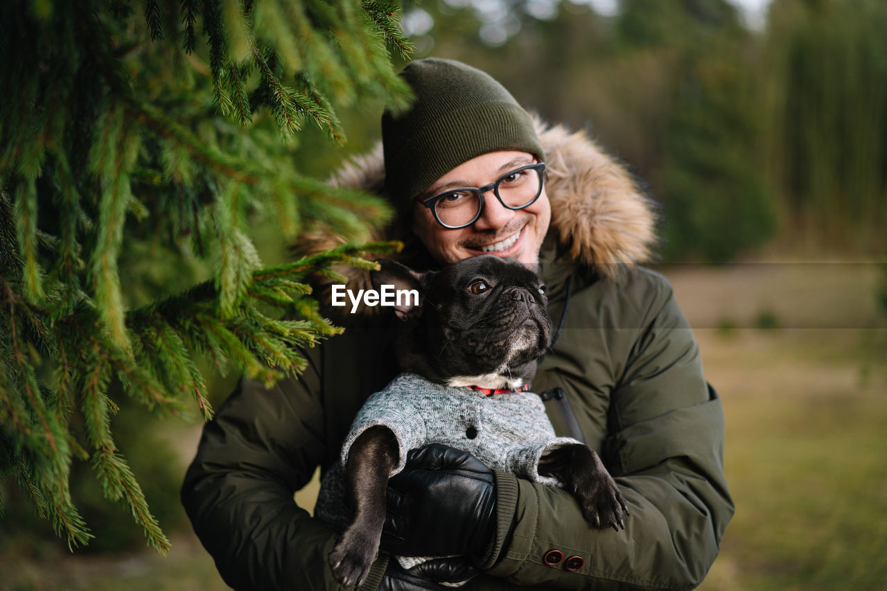 Portrait of mature man with french bulldog dog in forest