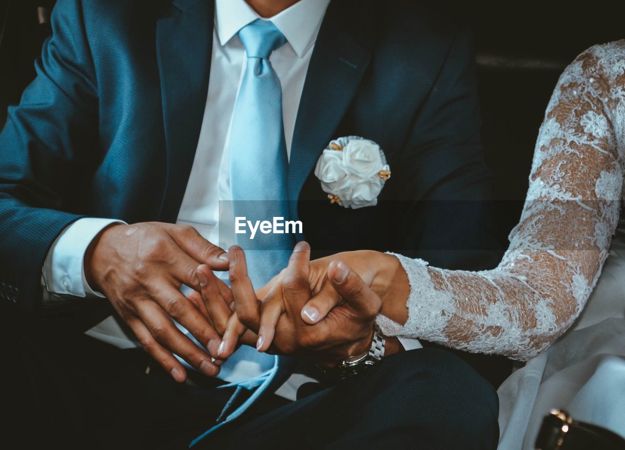 Midsection of bride and bridegroom holding hands during wedding ceremony