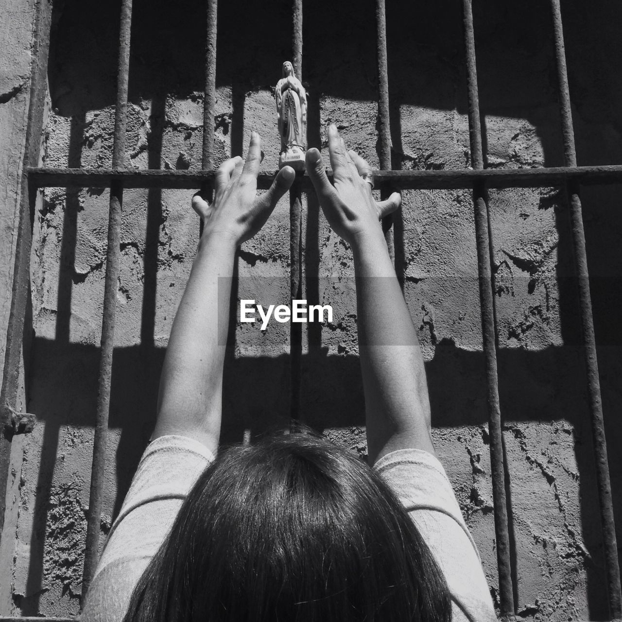 Woman praying before prison bars