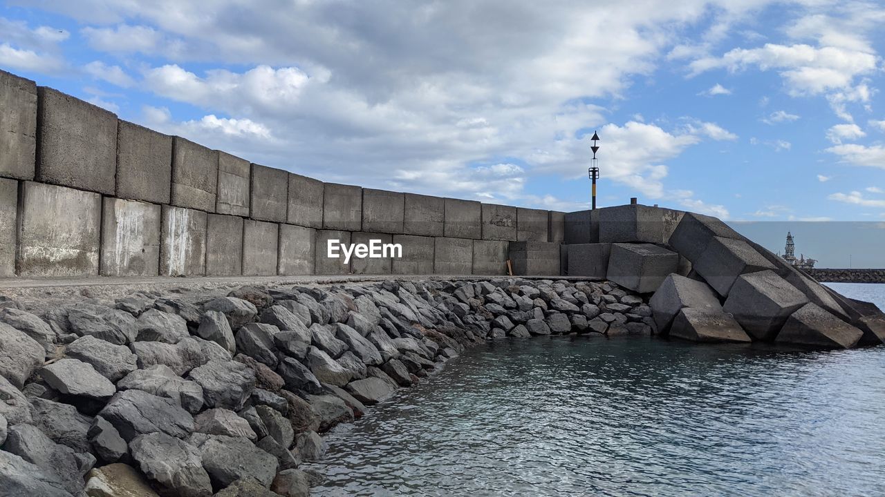 water, architecture, sky, cloud, built structure, sea, nature, wall, stone wall, day, outdoors, no people, rock, building exterior, industry, wall - building feature