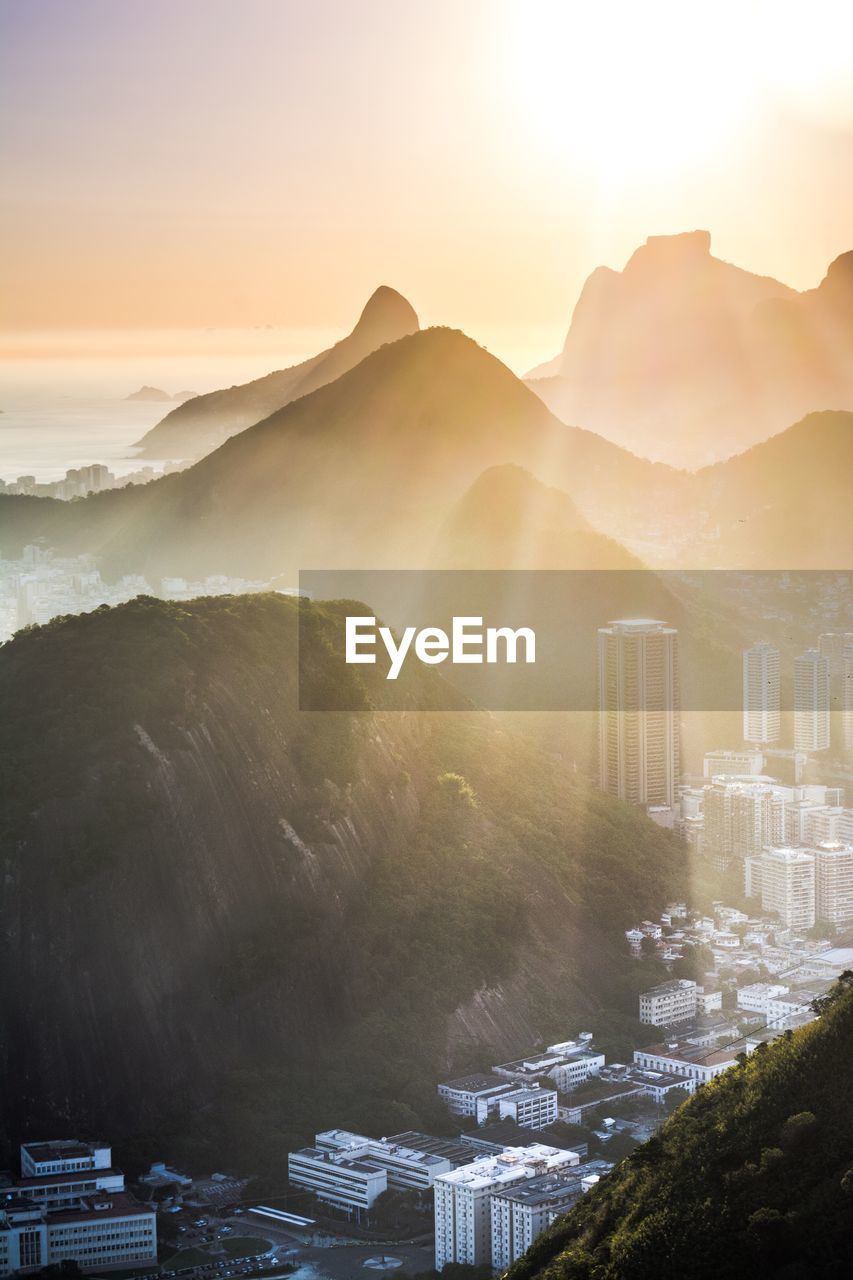 Aerial view of buildings and mountains against sky during sunset