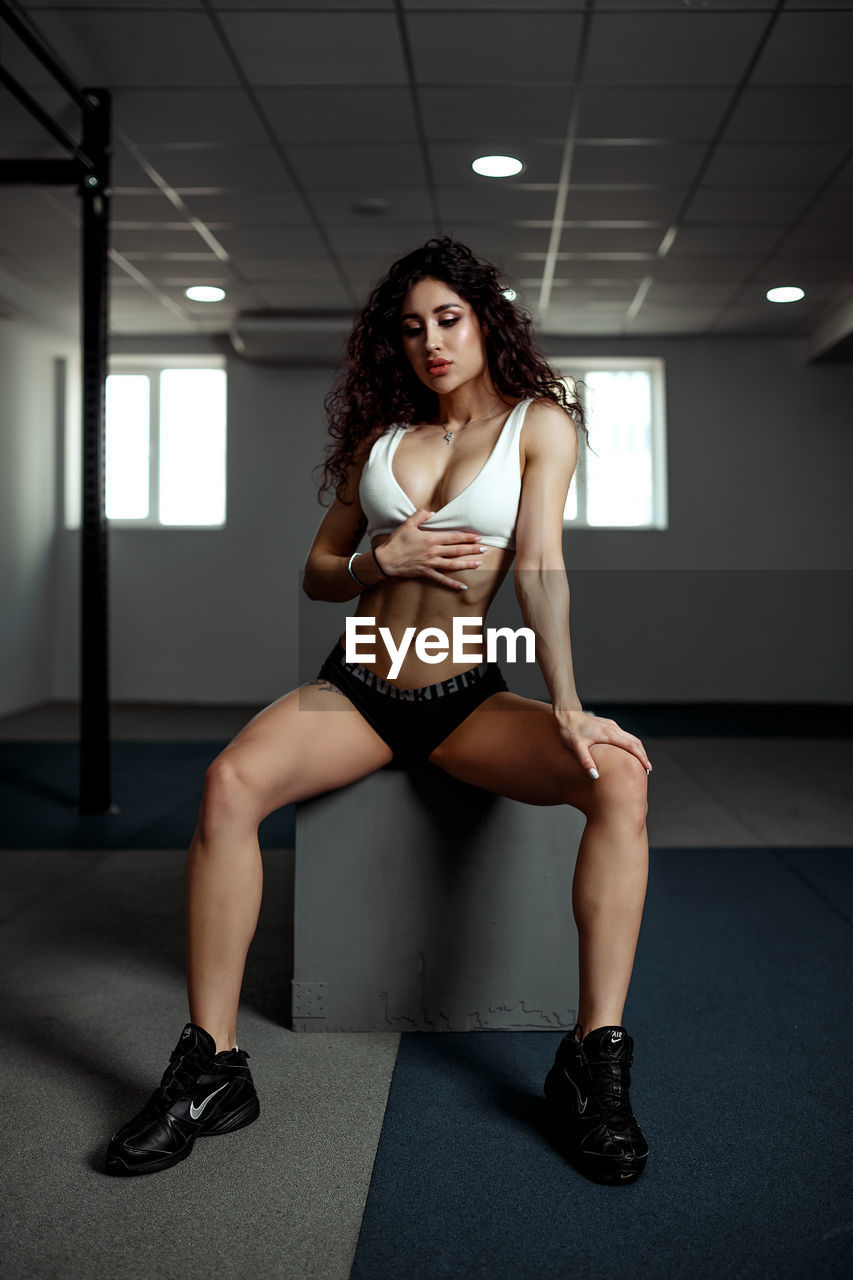Young woman sitting on box in gym