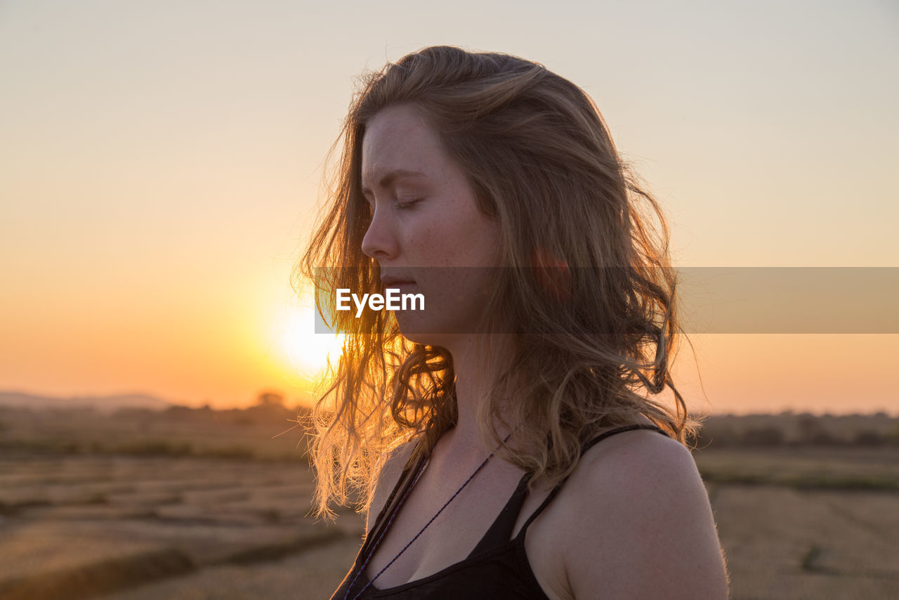 Close-up of beautiful woman against sky during sunset