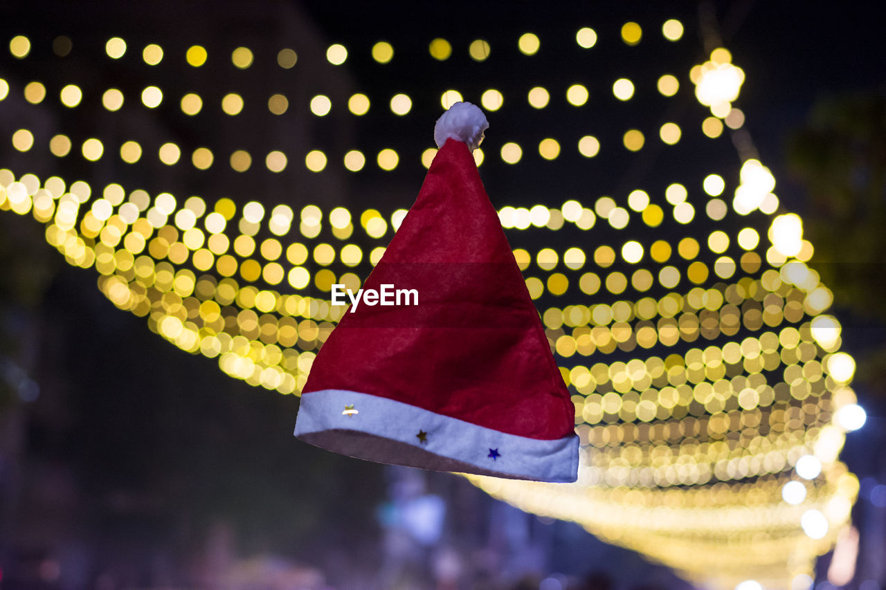 Santa hat in mid-air against illuminated lighting equipment at night