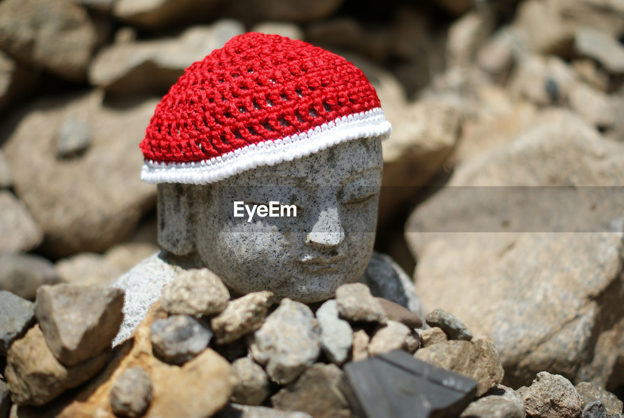 Close-up of stone buddha with red hat