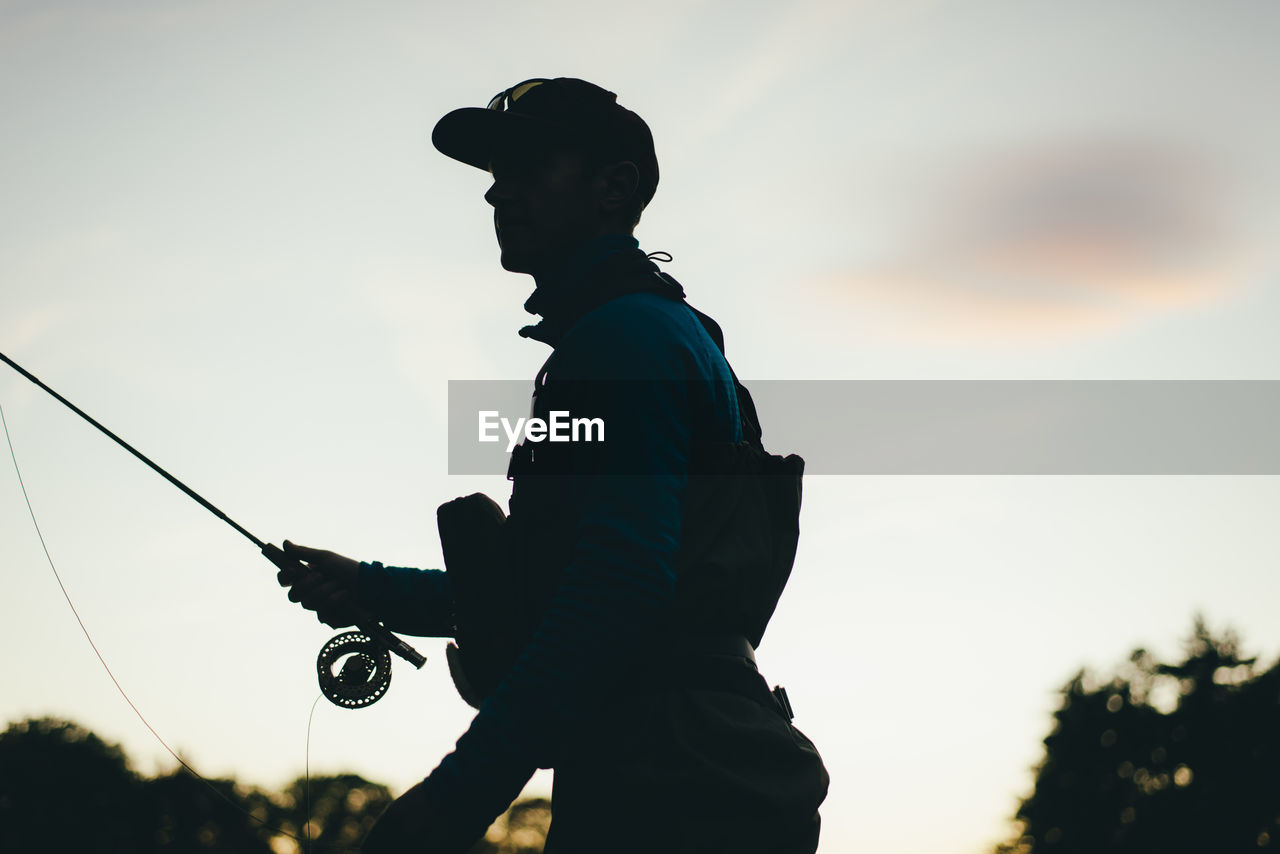 Silhouette of fly-fisherman during evening light