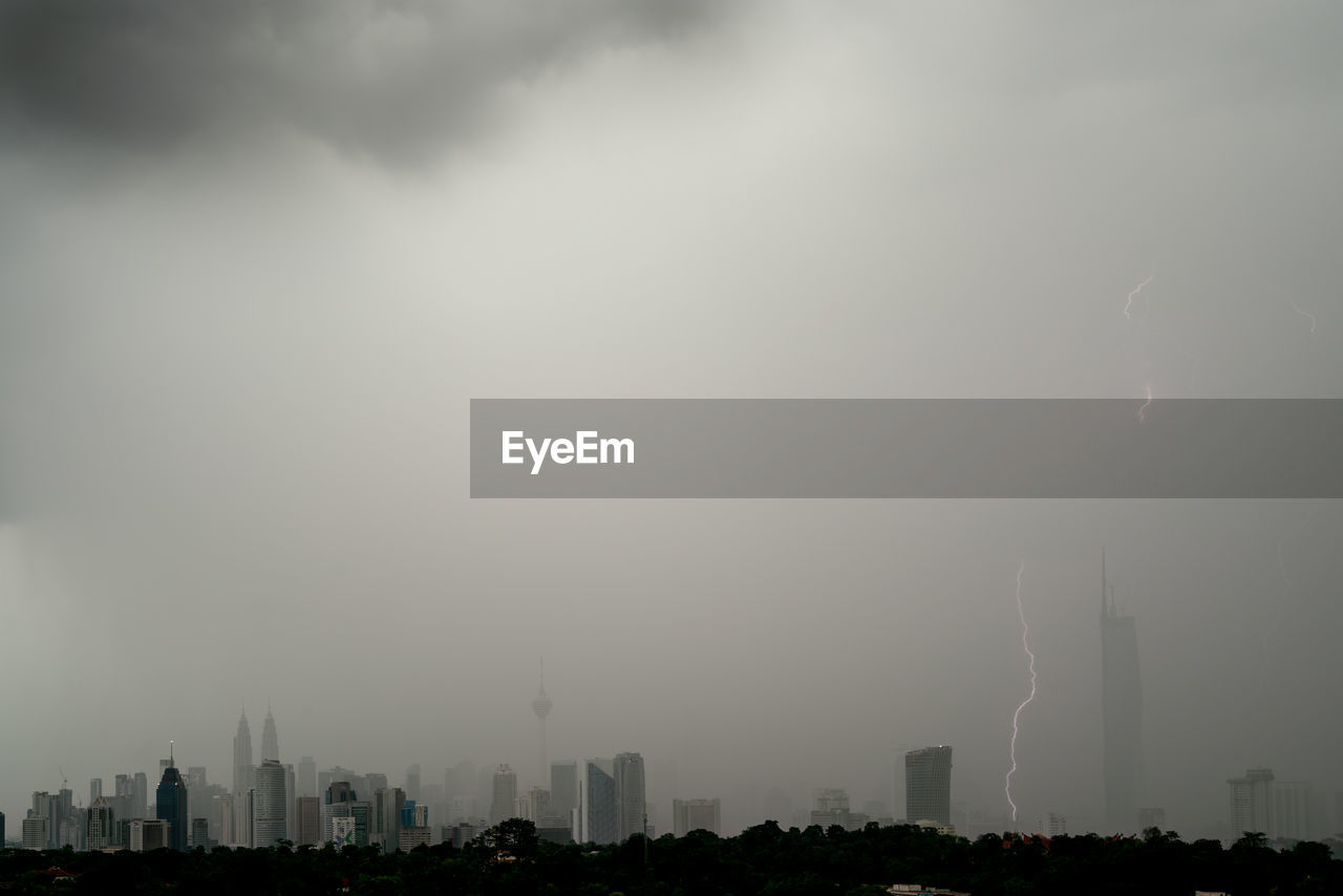 lightning, storm, city, building exterior, thunder, architecture, sky, cloud, thunderstorm, built structure, cityscape, building, landscape, power in nature, storm cloud, nature, environment, overcast, urban skyline, office building exterior, skyscraper, rain, no people, fog, city life, outdoors, beauty in nature, night, dramatic sky, extreme weather, wet, dark, communication, forked lightning, torrential rain, monsoon, environmental issues, travel destinations, residential district, warning sign, atmospheric mood