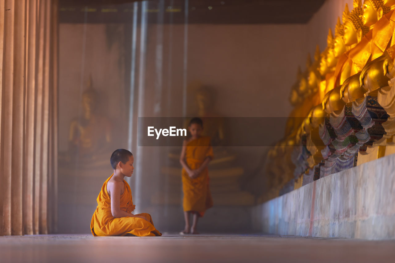 Side view of boy praying in buddhist temple