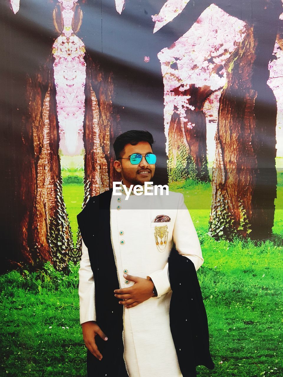 DIGITAL COMPOSITE IMAGE OF MAN WEARING SUNGLASSES STANDING BY PLANTS