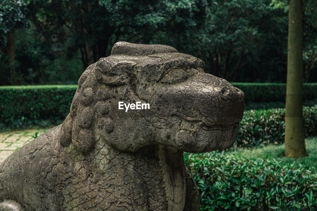 Close-up of sitting kylin statue against trees in park