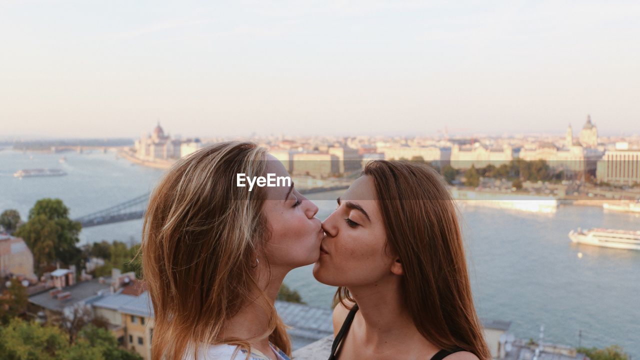 Lesbian couple kissing against cityscape