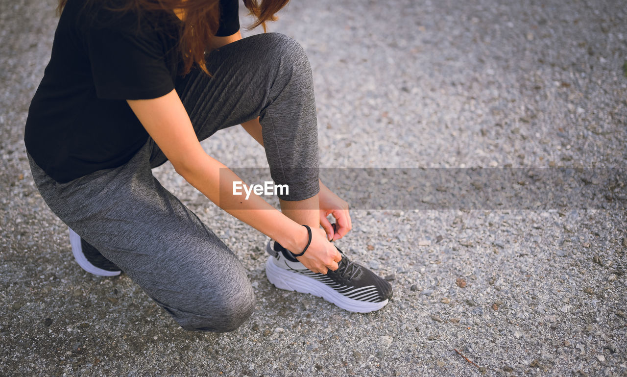 Young women knee sitting and wrapping a shoelace , workout , inspiration and motivation concept