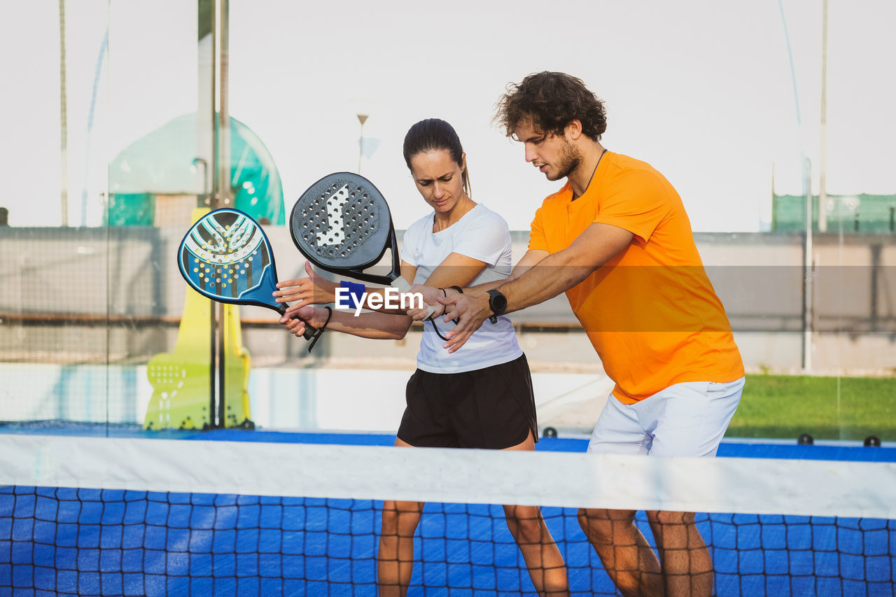 Man and woman holding tennis racket