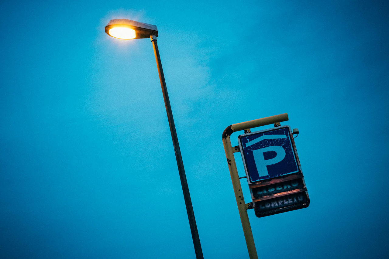 Low angle view of illuminated street light and signboard against sky