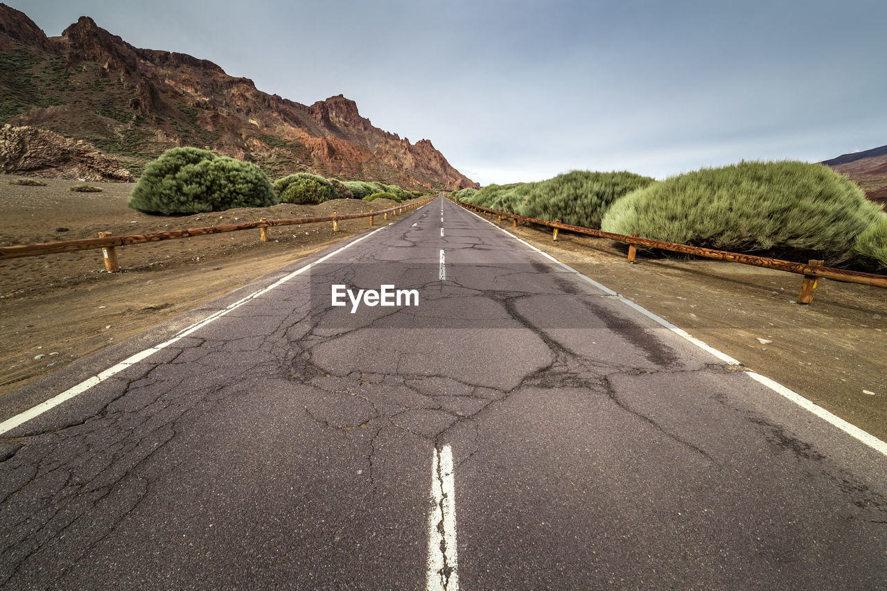 Road leading towards mountain against sky