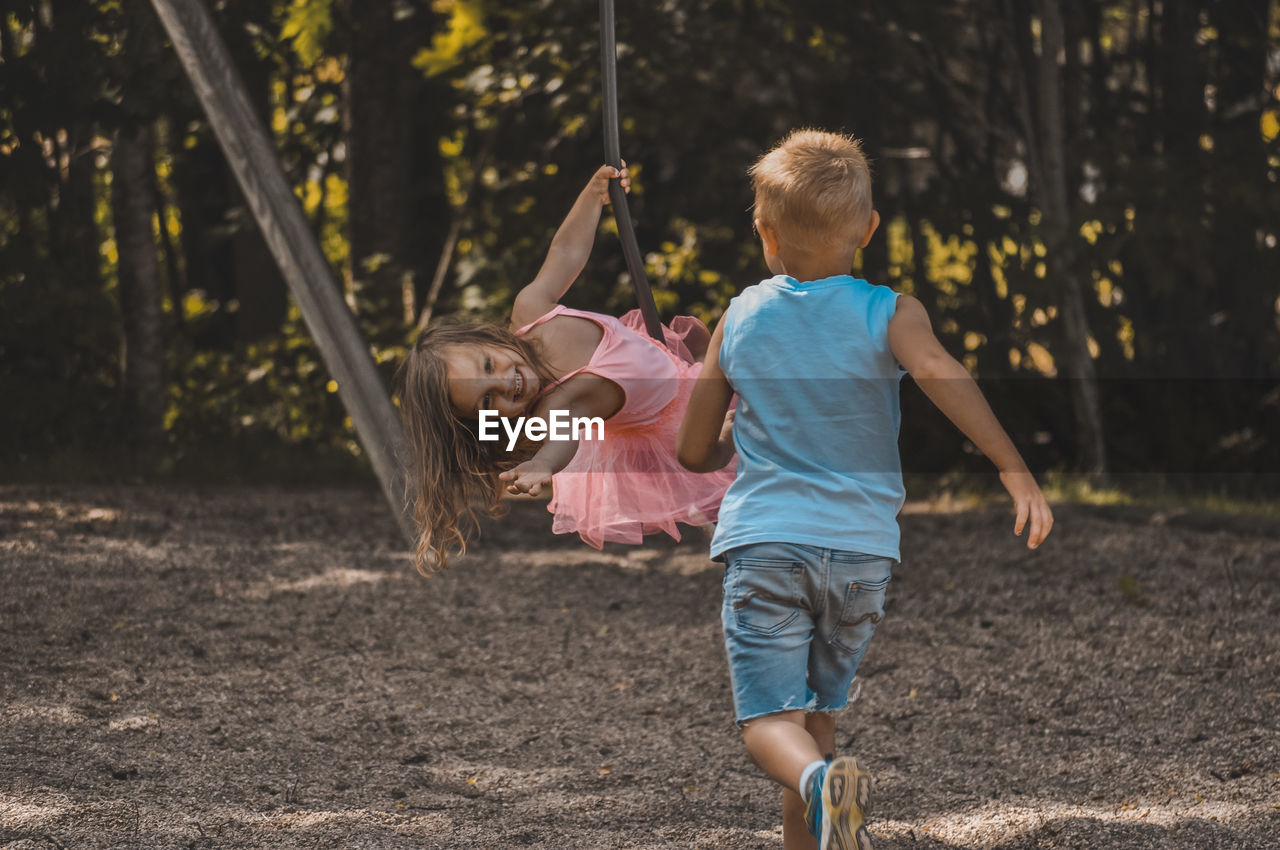 Rear view of girl and boy enjoying on playground 