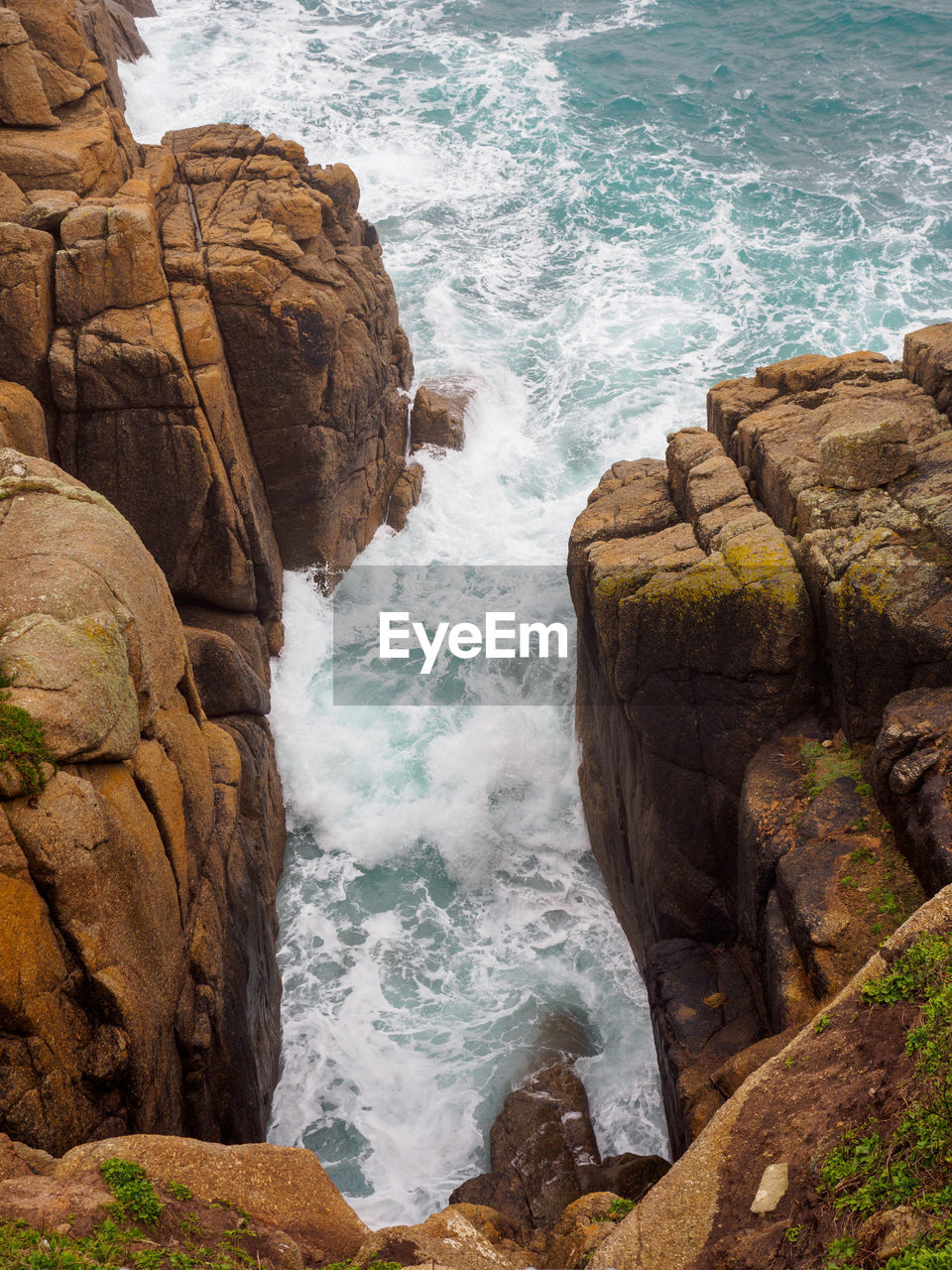Waves crash between the prismatic granite cliffs of porthcurno beach. cornwall, united kingdom.