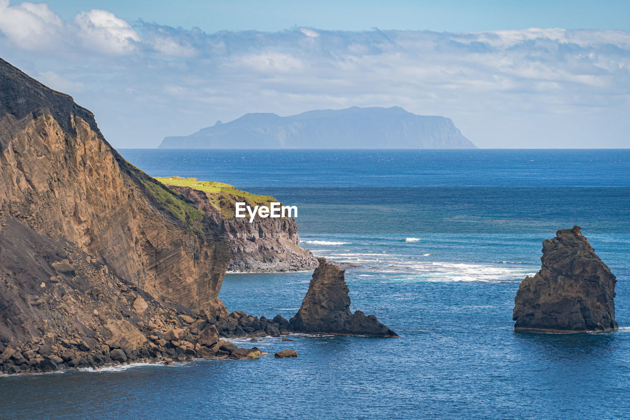 Scenic view of rocks in sea against sky