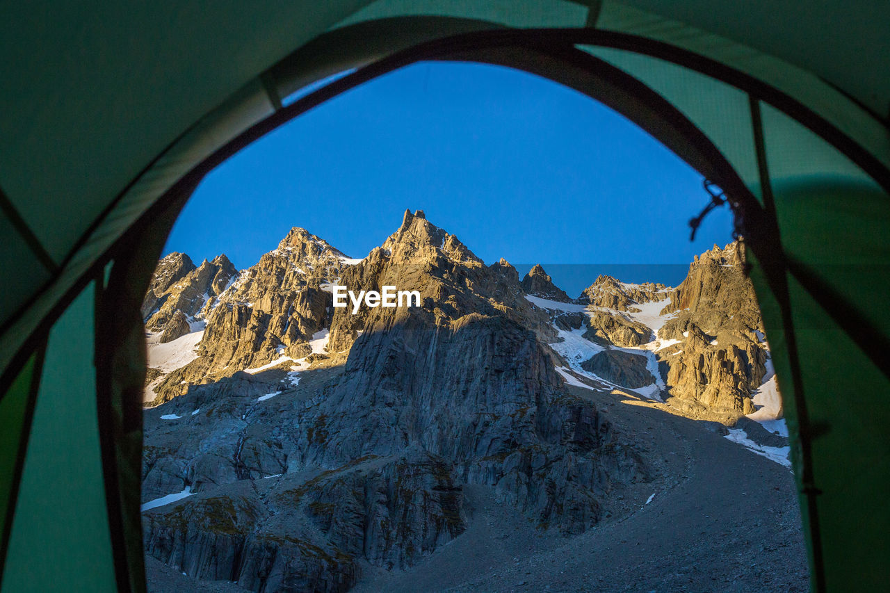 Snowcapped mountains seen through tent against clear sky