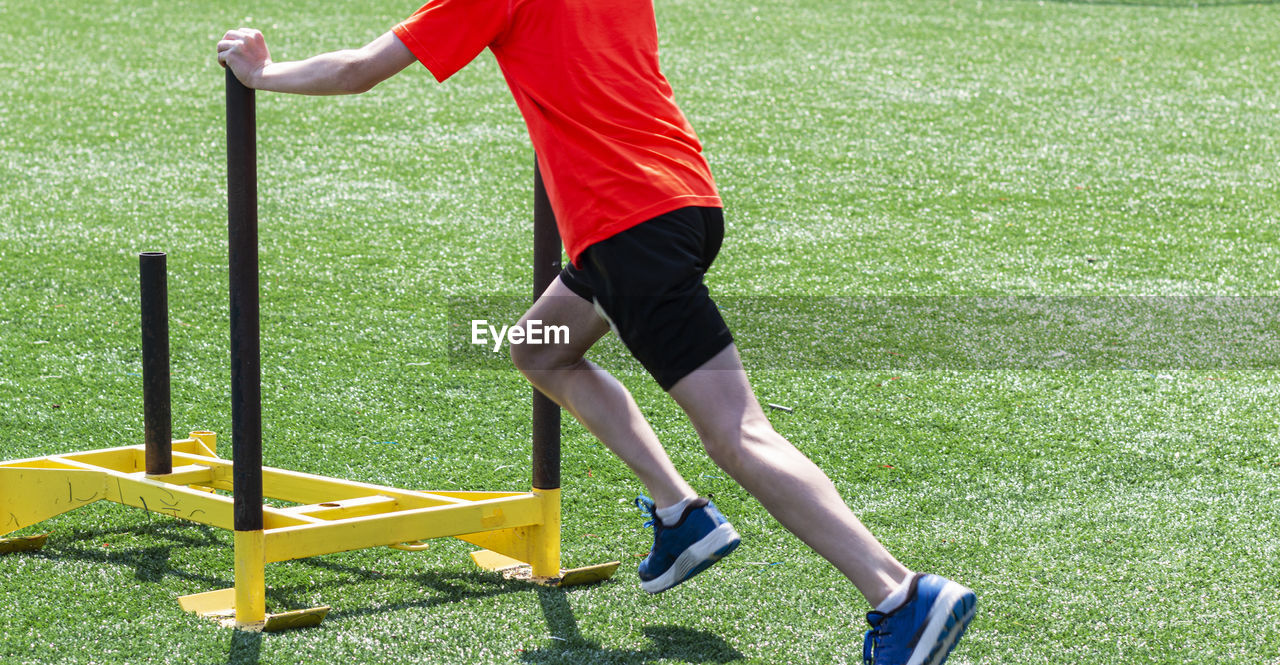 Low section of man exercising with sled on turf ground