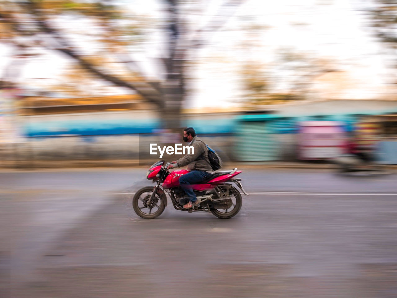 BLURRED MOTION OF MAN RIDING MOTORCYCLE ON STREET