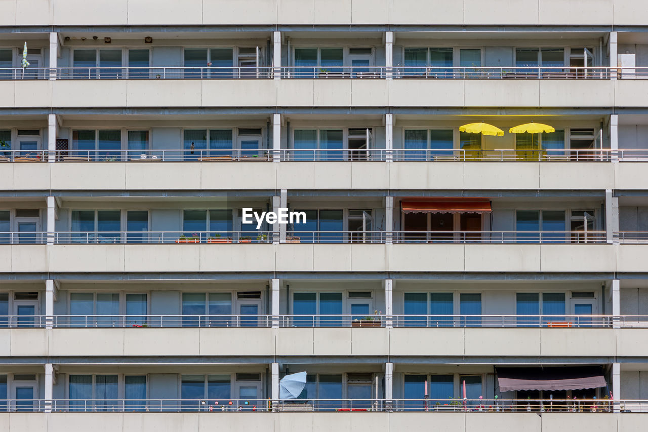 Facade of a big apartment building with yellow sunshades on one of the balconies