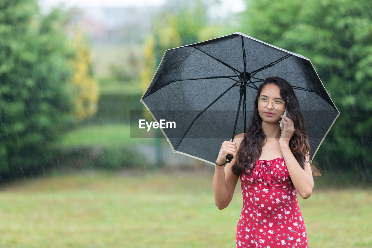 portrait of young woman with umbrella standing outdoors