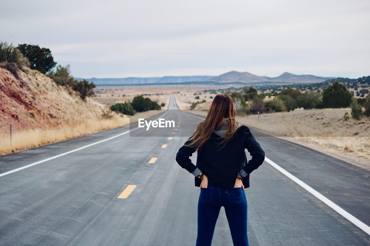 Rear view of woman standing on road against sky