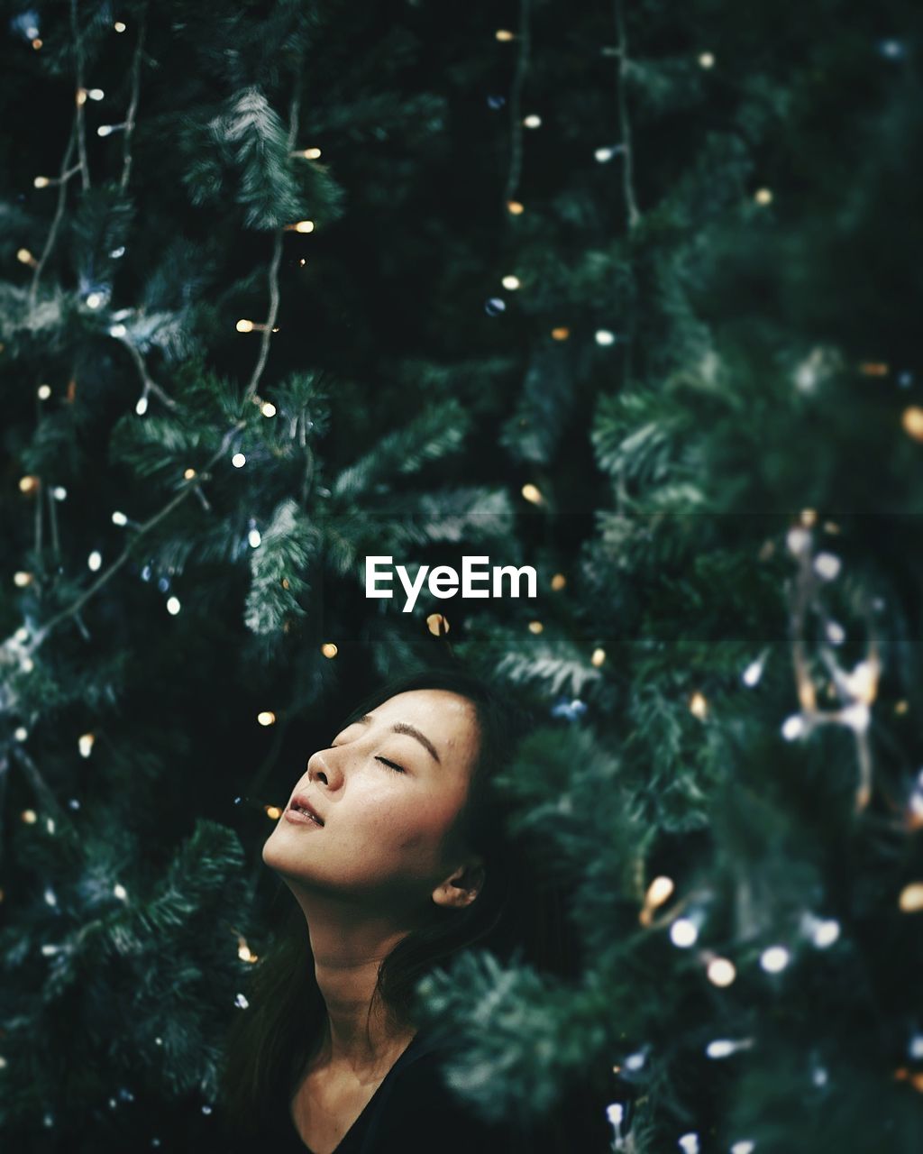 Close-up of young woman against christmas tree