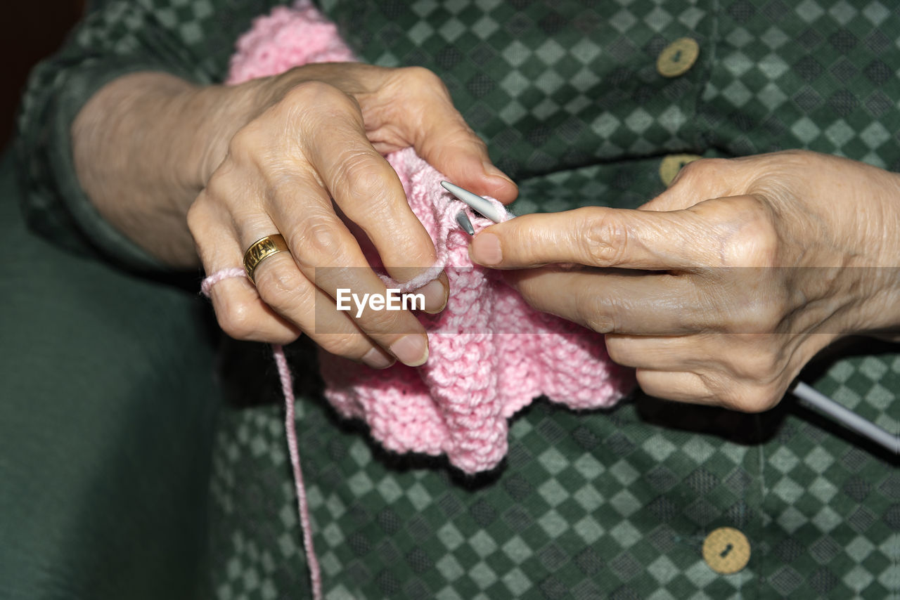 Midsection of senior woman knitting wool at home